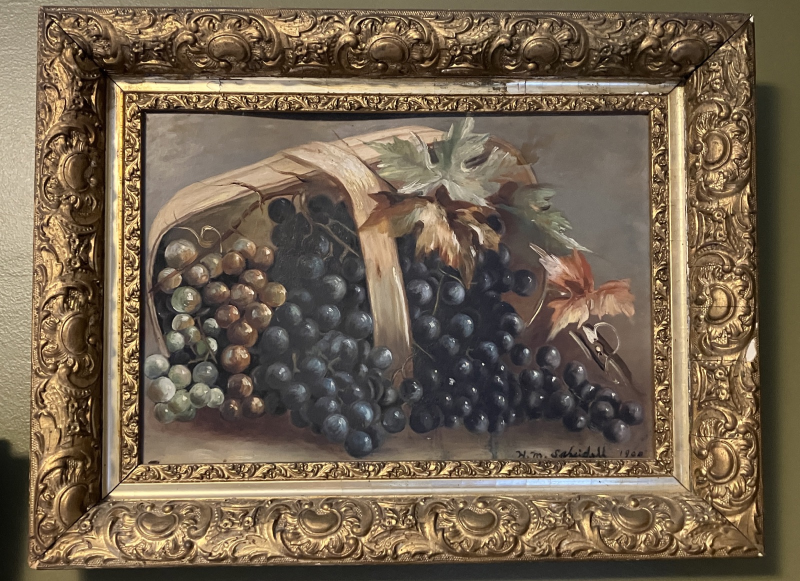 A framed Scheidell painting of grapes spilling from a basket